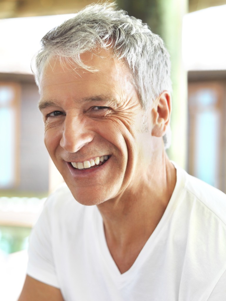 Mature man smiling because he uses proper technique to keep his denture clean