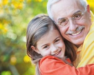 Smiling grandfather hugging his adorable granddaughter